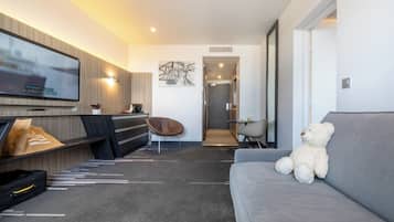 Uma sala de estar moderna com televisão de tela plana, um sofá, um urso e um design minimalista.