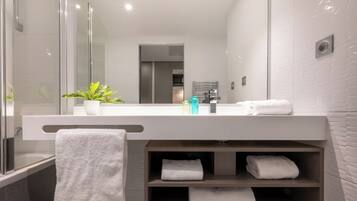 A modern bathroom with a glass shower enclosure, a white sink with a mirror above it, and a towel rack with folded towels.