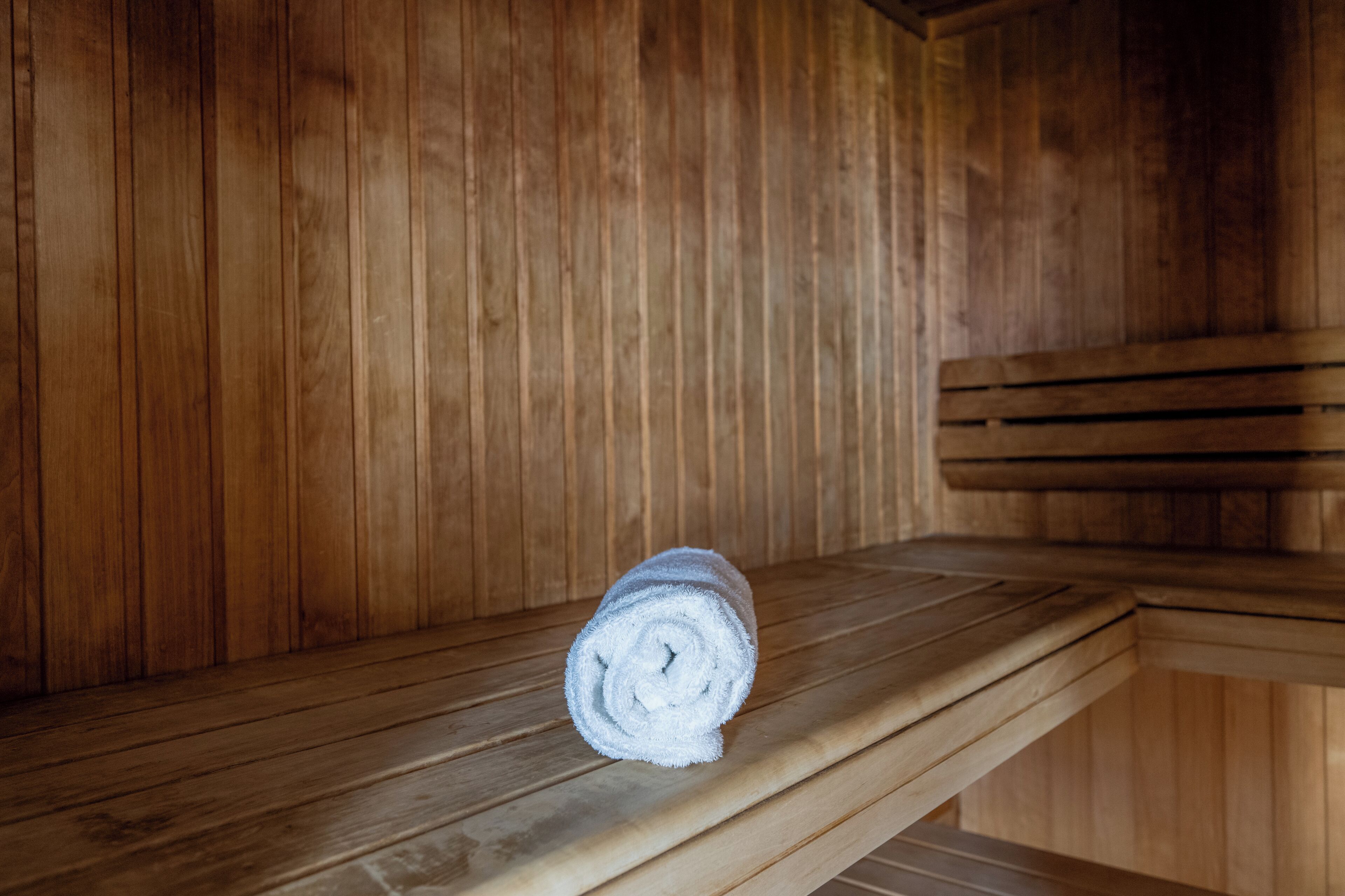 Un banco de sauna de madera con una toalla enrollada encima.