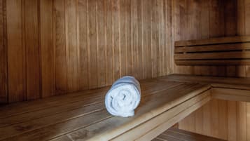 Un banco de sauna de madera con una toalla enrollada encima.