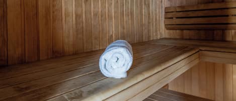 Un banco de sauna de madera con una toalla enrollada encima.