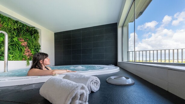 A spa room with a hot tub, a wall with greenery, and a view of the sky. - Nemea Appart Hotel Concorde Toulouse Gare Matabiau (Toulouse)