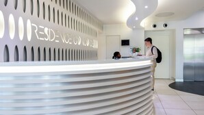 A modern reception desk with a curved design and a wall-mounted sign that reads "RESIDENCE OF CONCORDIA." - Nemea Appart Hotel Concorde Toulouse Gare Matabiau (Toulouse)