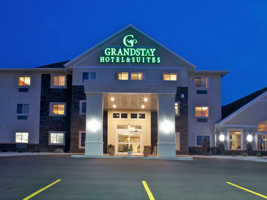 Edificio del hotel GrandStay & Suites con una entrada destacada, varias ventanas y un estacionamiento.