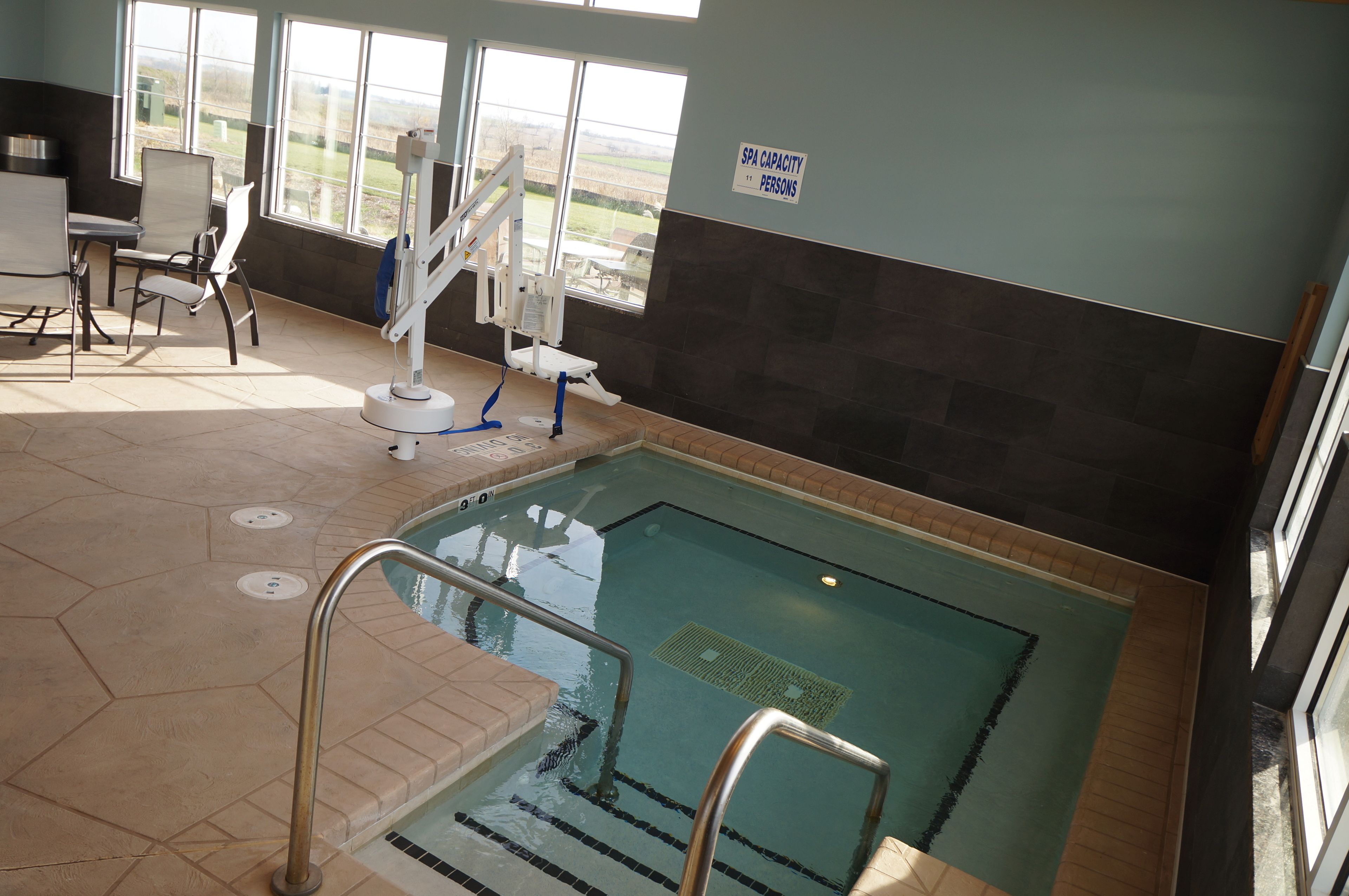 An indoor swimming pool with a spa capacity sign, a changing room, and a view of the outdoors.