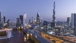 A rooftop terrace with a cityscape view, including modern skyscrapers and a prominent tower. - Shangri-La Residences and Apartments (Dubai)