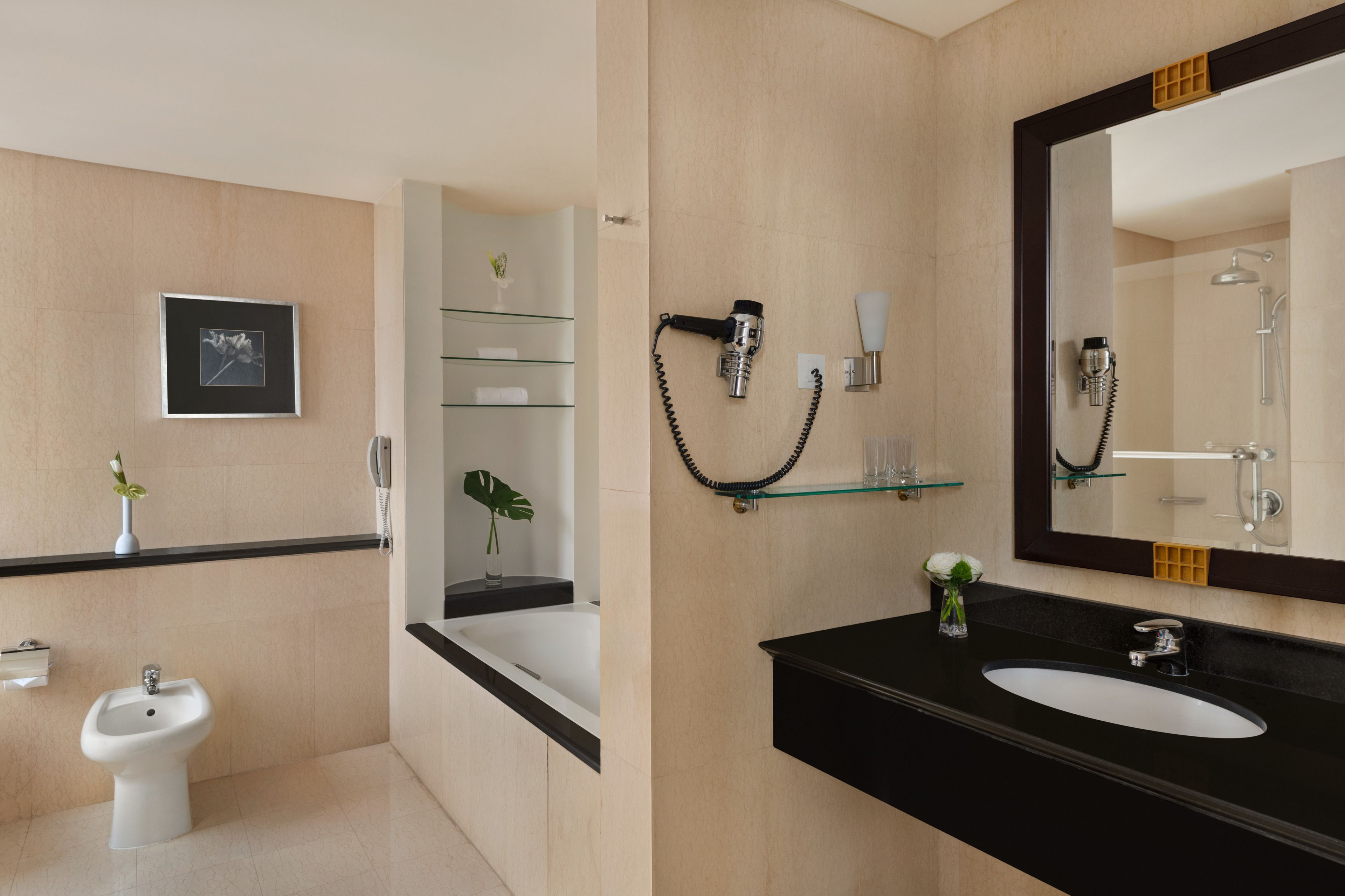 Ein modernes Badezimmer mit Bidet, großem Spiegel, Waschbecken und Duschbereich.