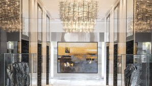 A modern lobby with a marble floor, a large chandelier, and glass display cases with sculptures. - Shangri-La Residences and Apartments (Dubai)