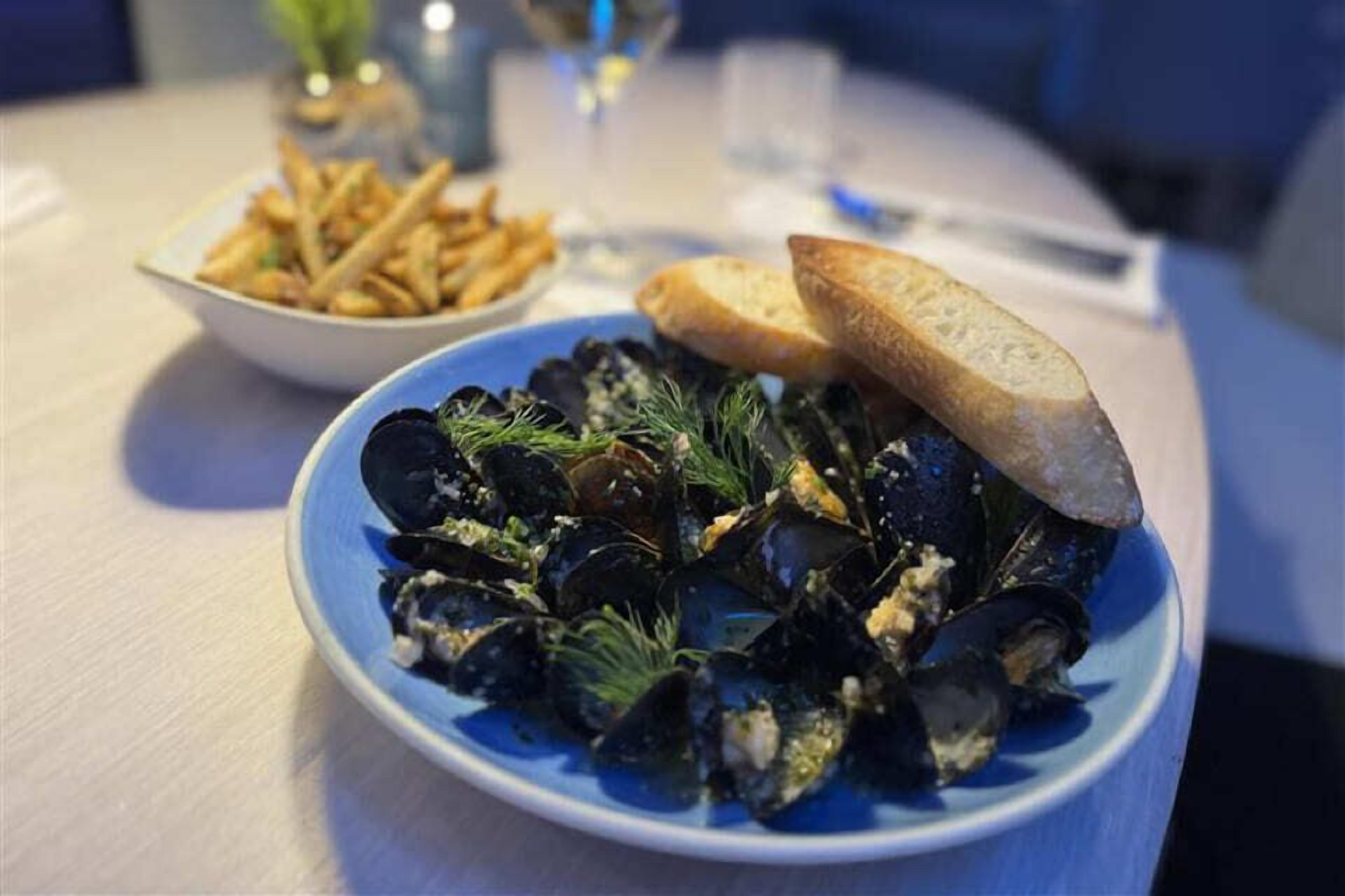 Un piatto di cozze con pane su un tavolo.