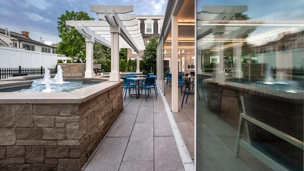 Un área de patio al aire libre con jacuzzi, asientos y una pérgola.