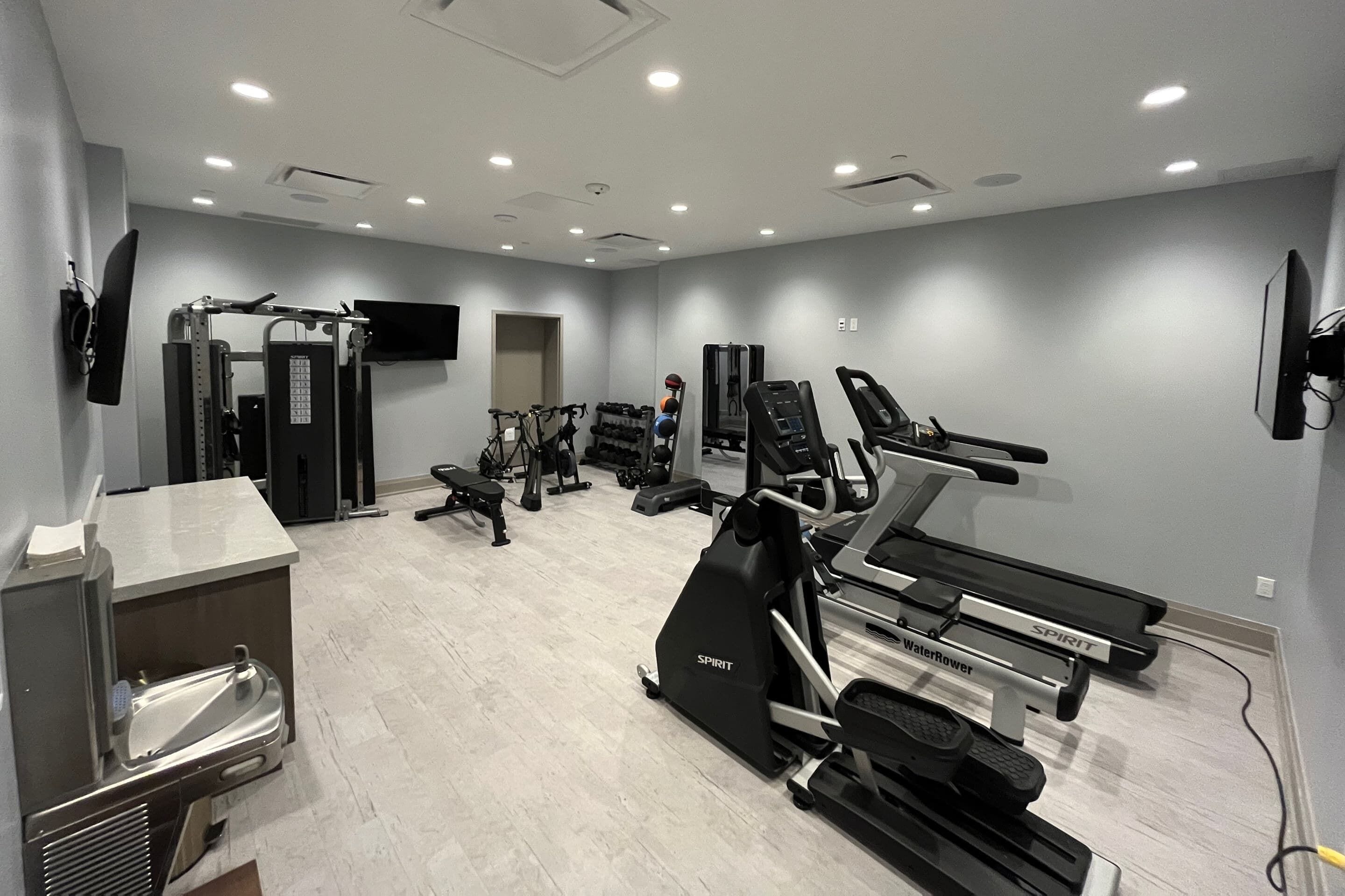 A gym with various exercise equipment including treadmills, weight machines, and a stationary bike.