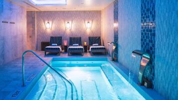 Un cuarto de spa con una piscina, tres sillas de masaje e iluminación empotrada.