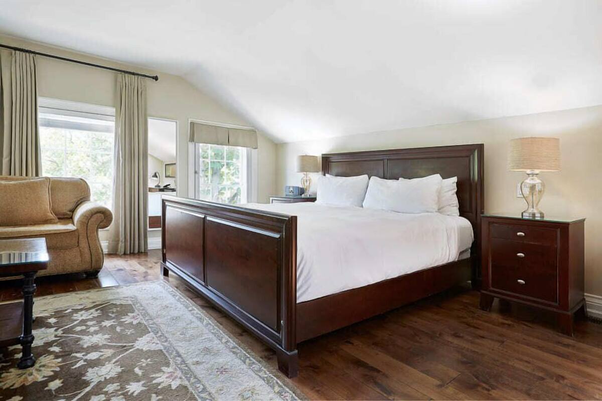 Une chambre à coucher avec un grand lit, une table de chevet, une chaise et une fenêtre.