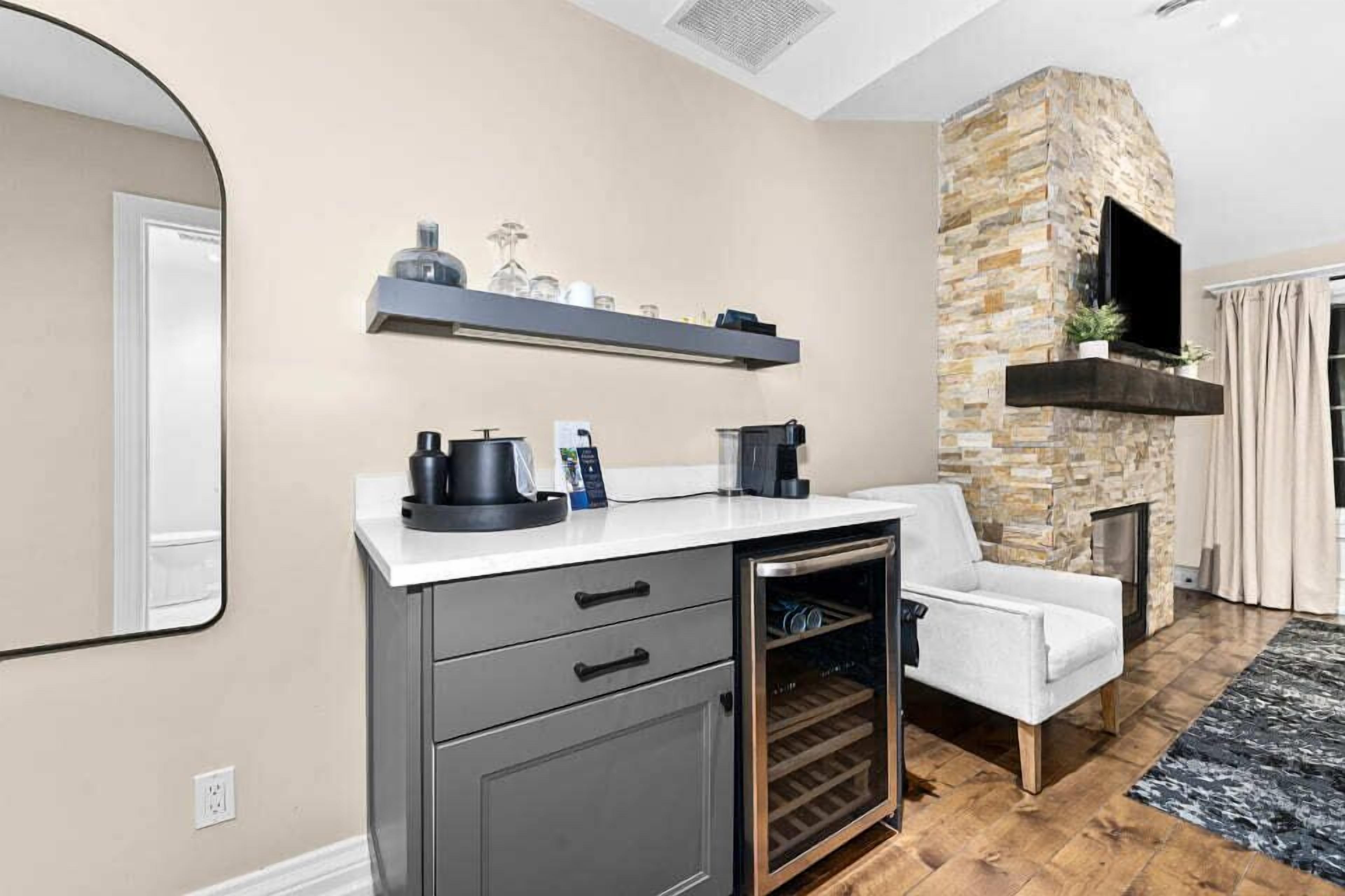 A modern kitchen with a stone accent wall, a built-in wine cooler, and a flat-screen TV mounted above the fireplace.