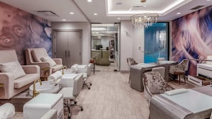 Un spa moderno con un mural grande, una araña y una mesa de recepción.