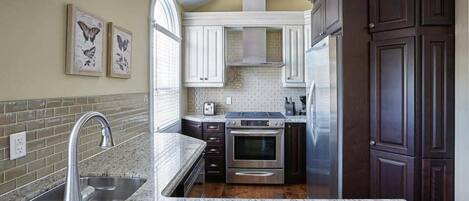 A kitchen with granite countertops, stainless steel appliances, and dark wood cabinets.