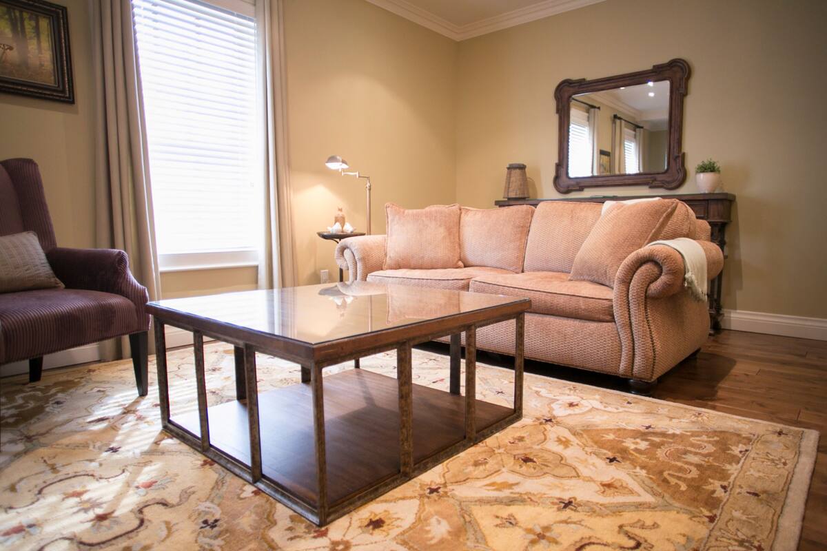 Un salon comprenant un canapé, un fauteuil, une table basse et un grand miroir au mur.