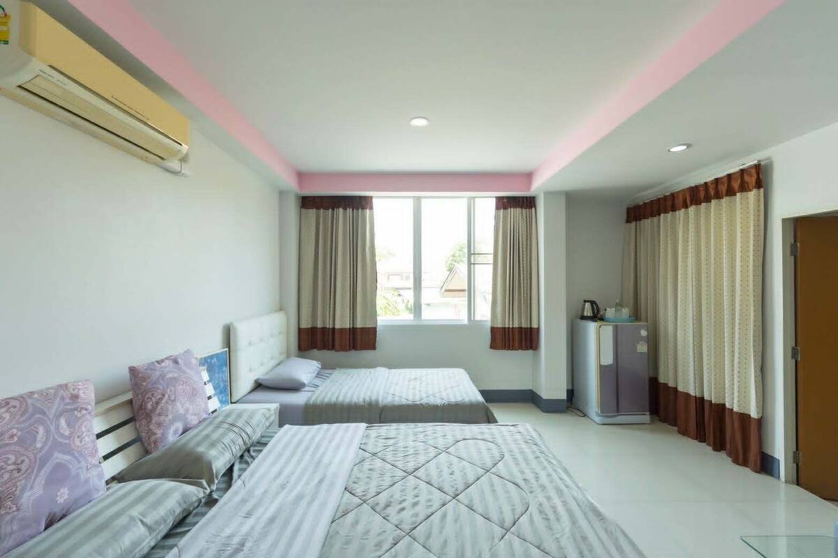 Una habitación de hotel con dos camas, una kitchenette y un ventanal con cortinas.