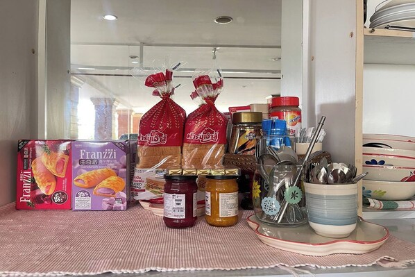 Una encimera de cocina con alimentos envasados, frascos de condimentos y utensilios de cocina.