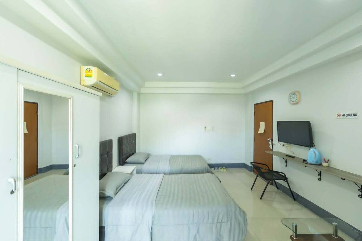 Una habitación de hotel con dos camas, un televisor, un reloj y un letrero de 'No Fumar'.