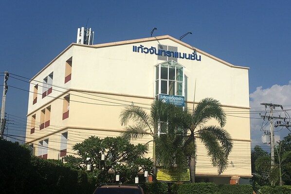 Un edificio con un cartel en idioma extranjero, rodeado de palmeras y cables de electricidad.