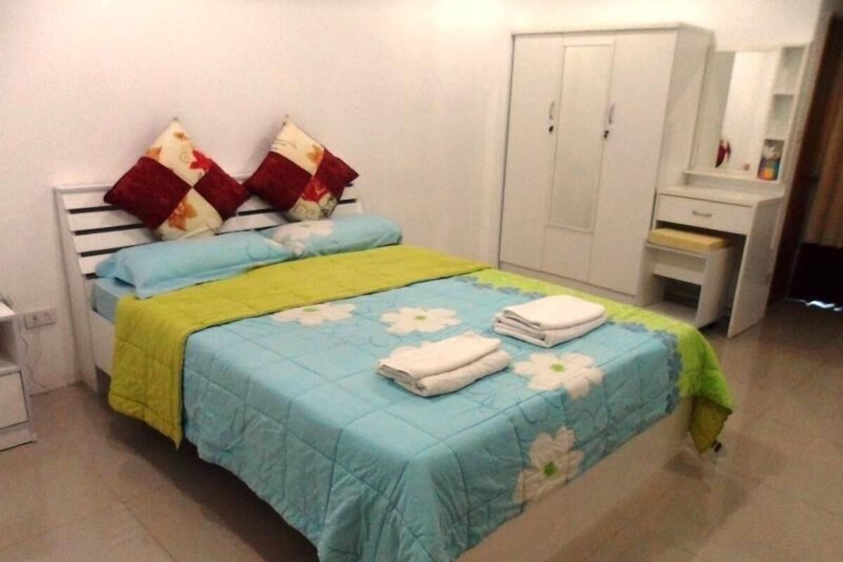 Un dormitorio con cama, armario y mesita de noche.