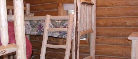 Una habitación tipo cabaña de madera con literas y una escalera.