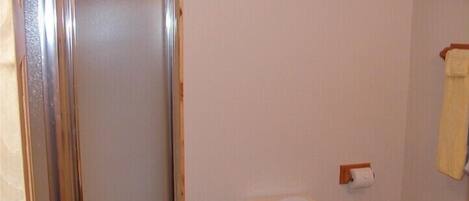 Un bagno piccolo con il water, una doccia e un asciugamano appeso al muro.