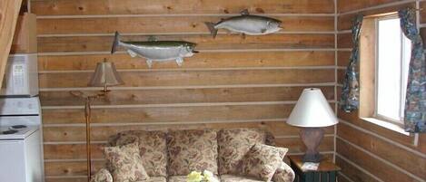 L'intérieur d'une cabine est décoré de boiseries, il y a un canapé, une lampe et deux poissons décoratifs accrochés au mur.