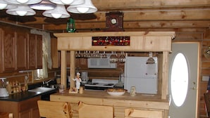 A wooden kitchen with a central island, bar stools, a clock, and hanging wine glasses. - Desperado (Custer)