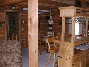 A wooden cabin interior with a dining area, a sofa, and a kitchen counter. - Desperado (Custer)