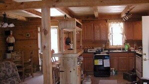 A rustic cabin interior with a wooden dining area, a kitchen with wooden cabinets, and a living room with a sofa. - Desperado (Custer)