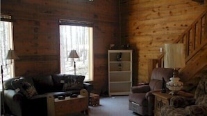 A cozy cabin interior with a sofa, armchair, and a small table with a lamp. - Desperado (Custer)
