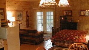A cozy room with a bed, a dining table, and a kitchen area.