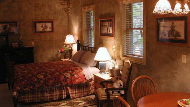 A cozy bedroom with a bed, a chair, a table, and a lamp.