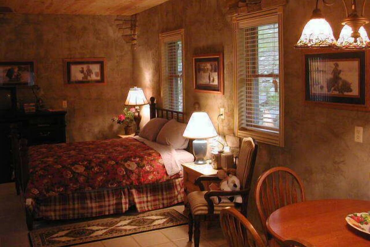 A cozy bedroom with a bed, a chair, a table, and a lamp.
