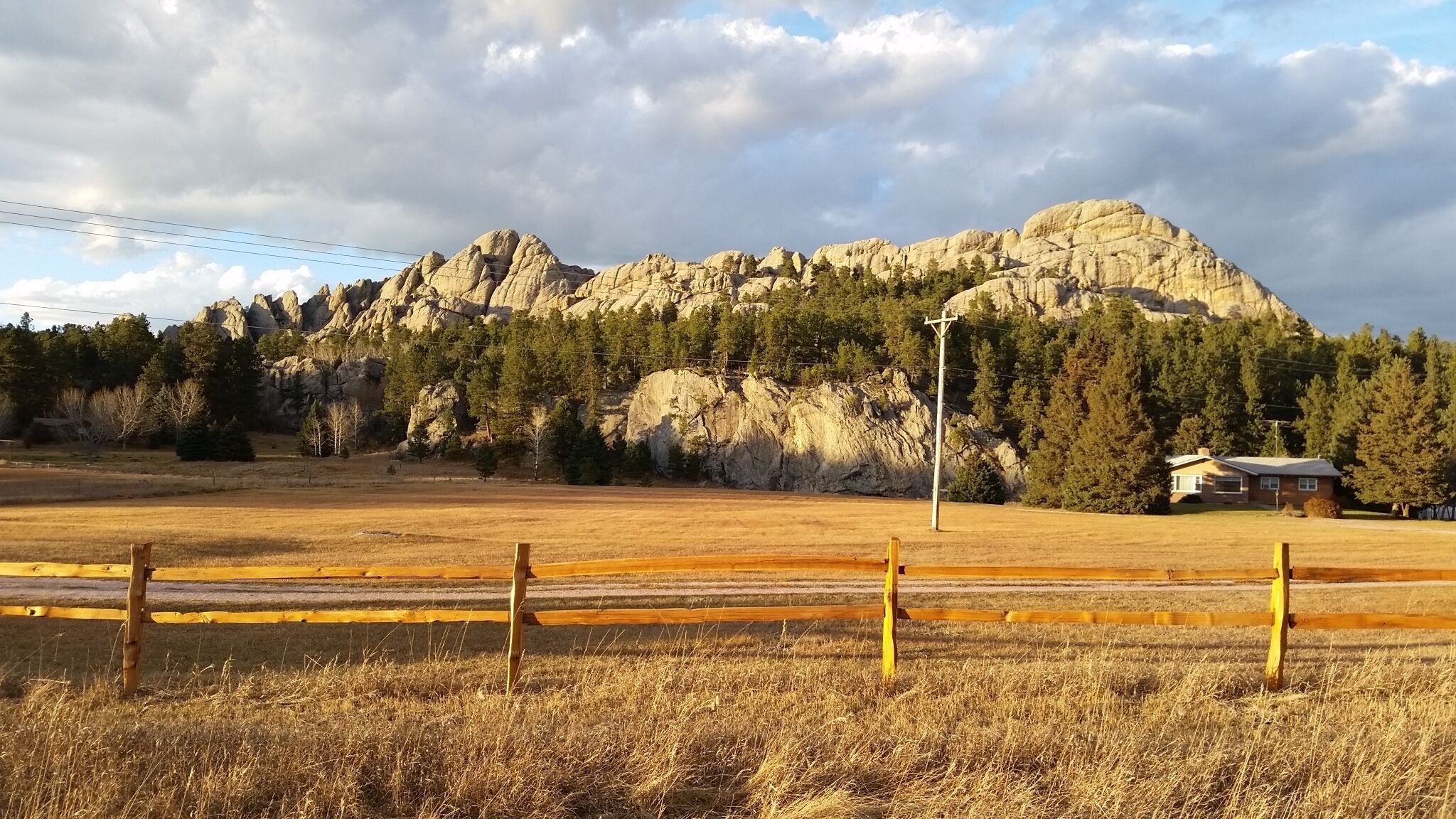 Paisaje rural con una montaña, un campo cercado y un edificio pequeño.