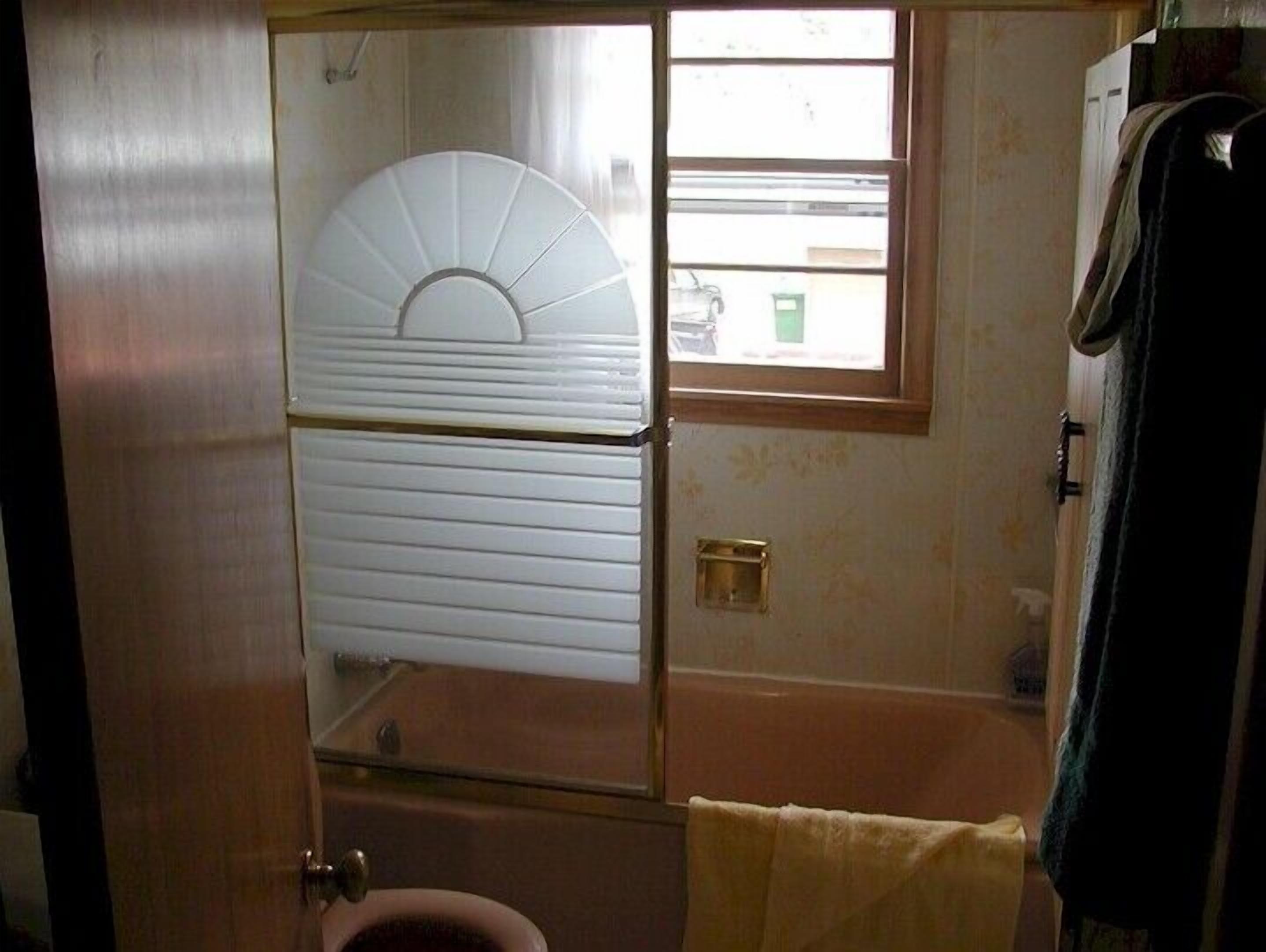 A bathroom with a toilet, a bathtub, and a window.