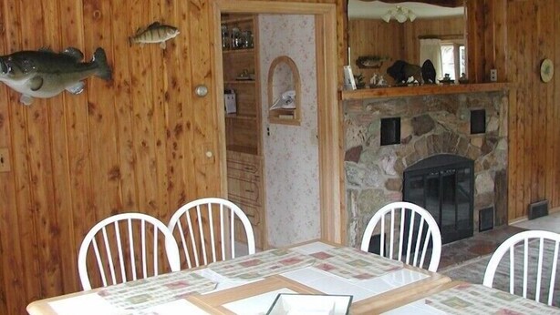 Un coin repas agrémenté d’un mur en bois, d’une cheminée en pierre et de poissons décoratifs fixés au mur.