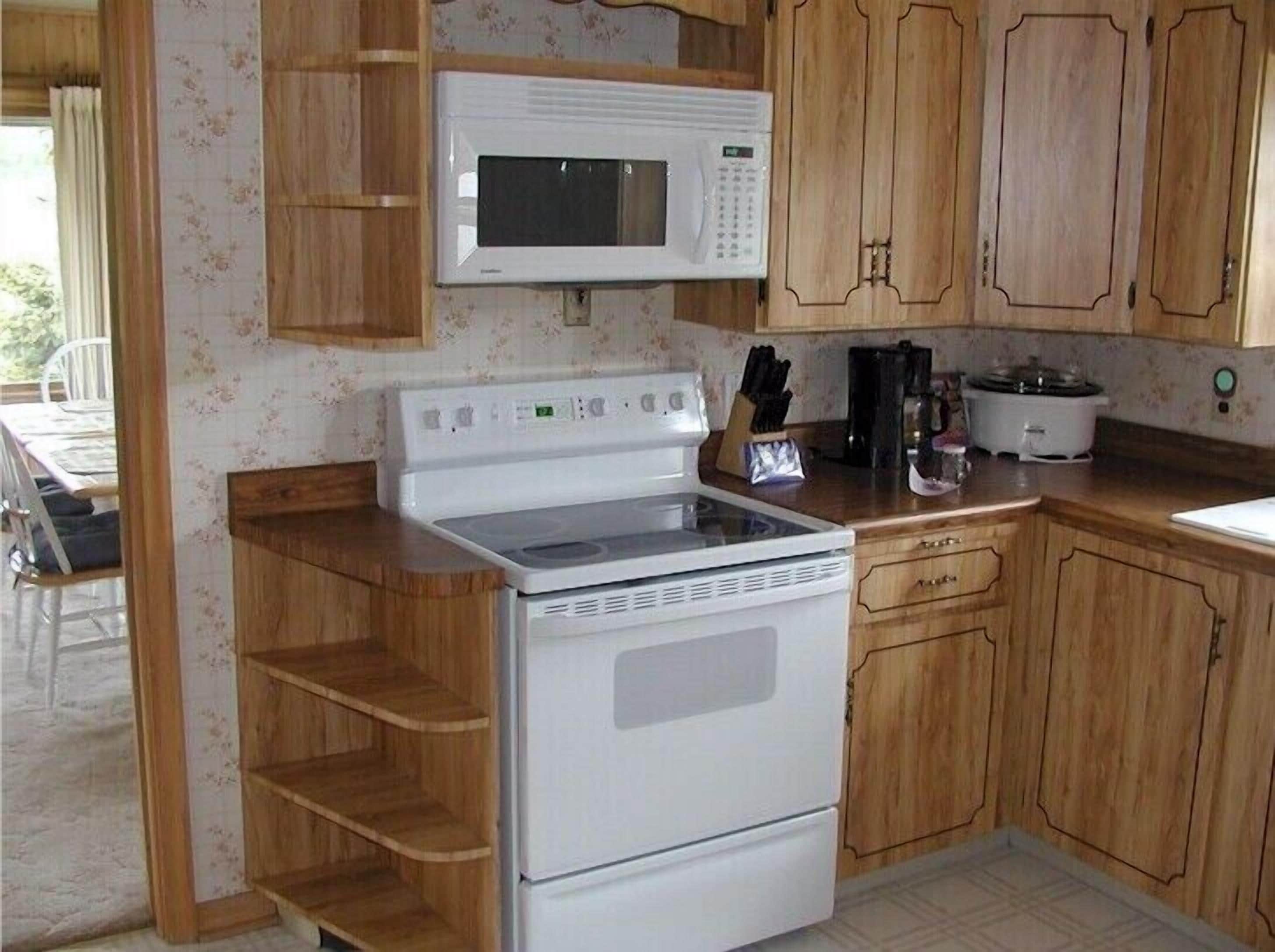 A kitchen with wooden cabinets, a microwave, a stove, and a slow cooker.