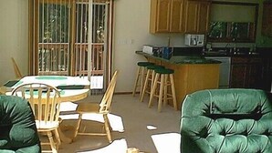 A living room with a dining table, chairs, a sofa, and a kitchen area with a counter and stools. - Thunderheart (Custer)