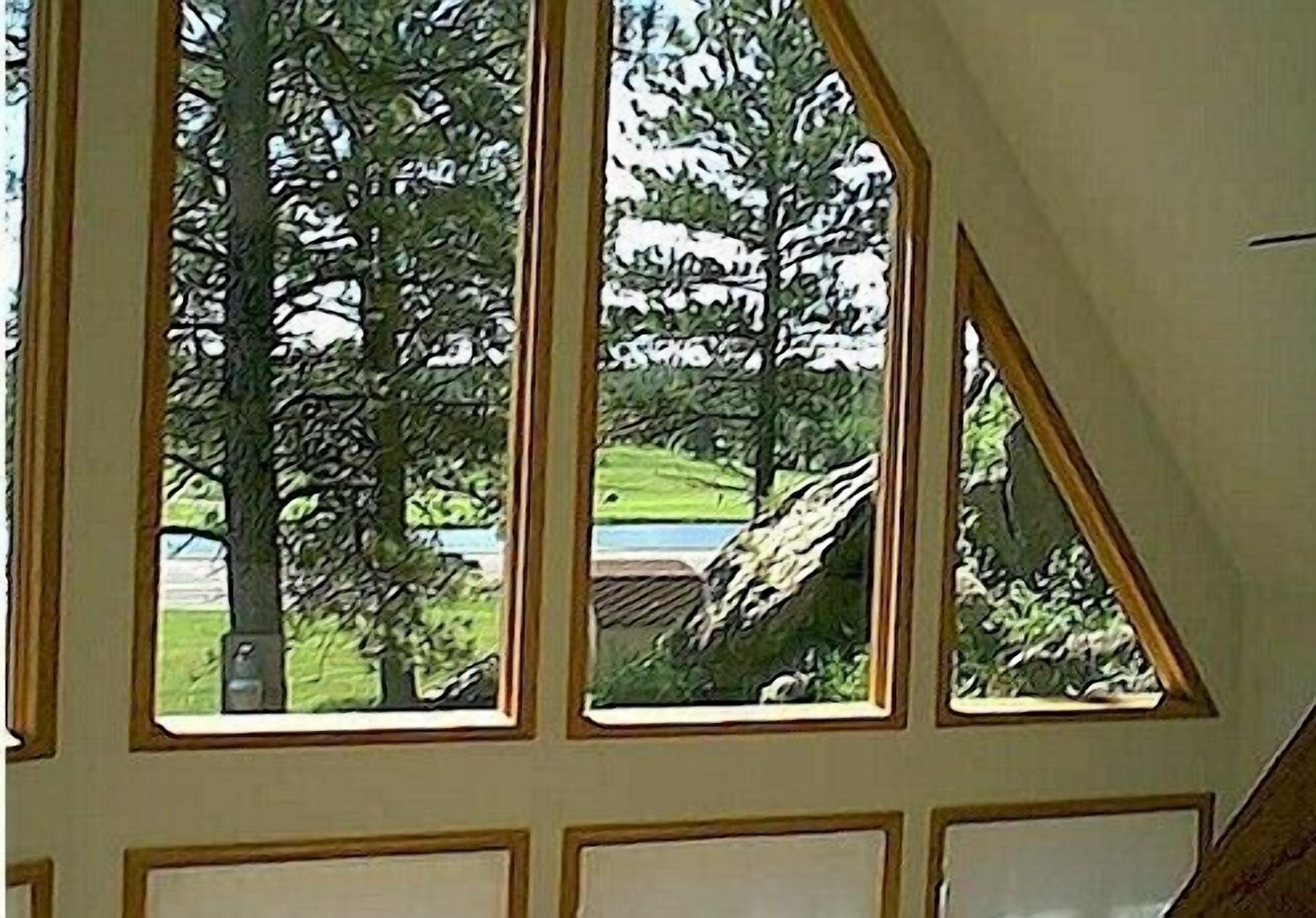 A room with large windows offering a view of trees and a body of water.