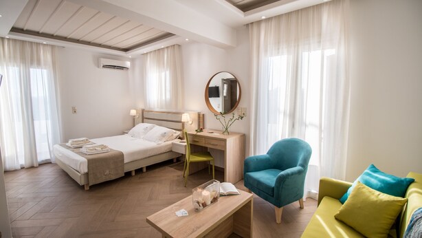 Een hotelkamer met een bed, bureau, stoel en een klein tafeltje met een boek en kaars.