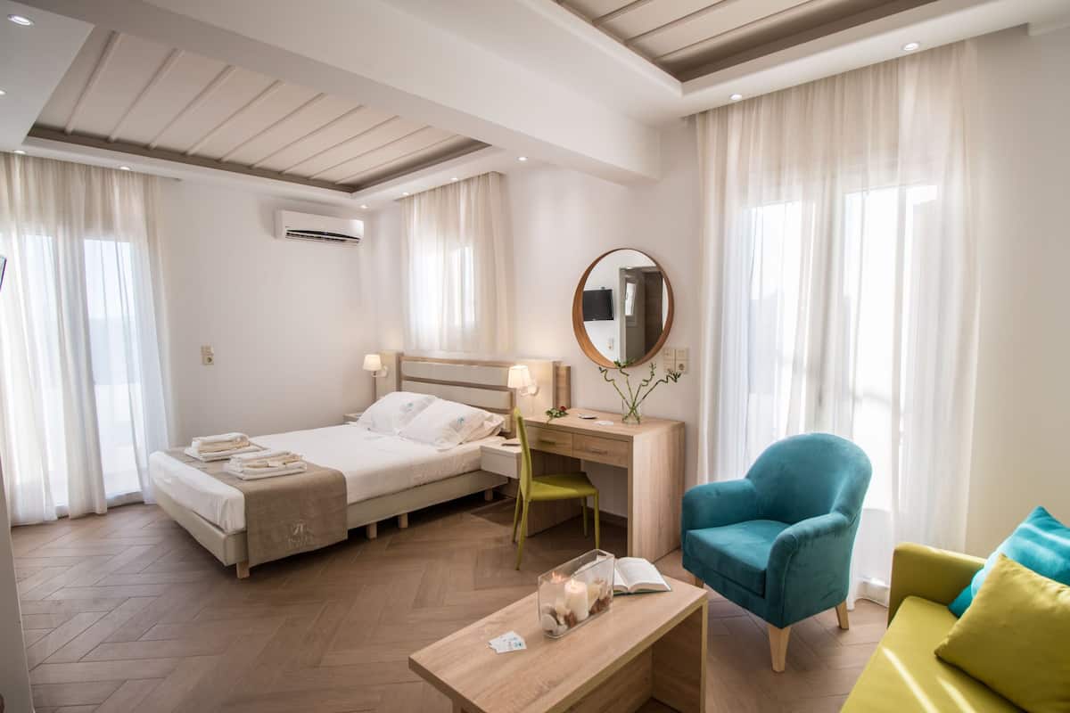 Een hotelkamer met een bed, bureau, stoel en een klein tafeltje met een boek en kaars.