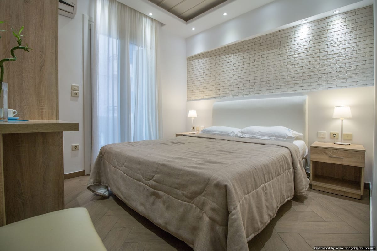 Een moderne slaapkamer met een groot bed, nachtkastjes en een wandlamp.