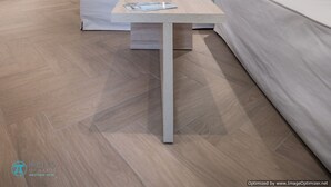 Een moderne woonkamer met een bank, een salontafel en een aan de muur bevestigde televisie.
