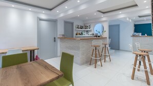 Een moderne keuken met een centraal eiland, barkrukken en een eethoek met een houten tafel en groene stoelen.