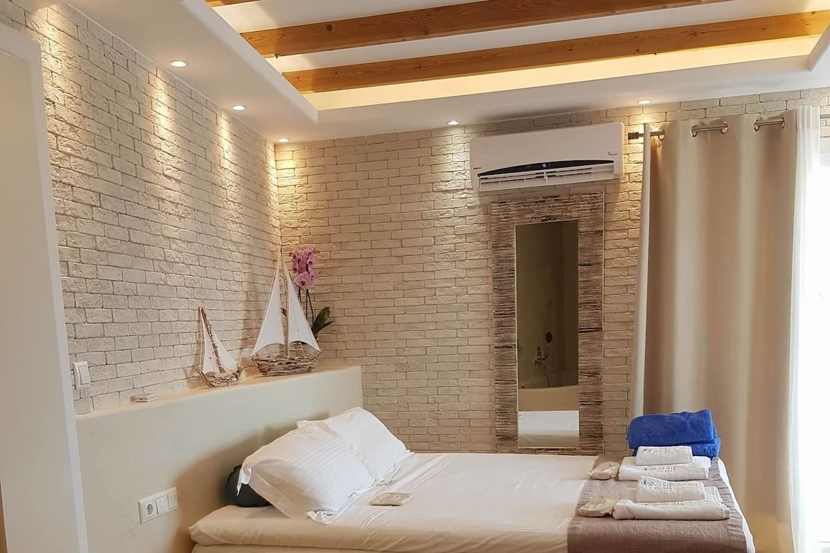 Een moderne slaapkamer met een houten plafond, een bakstenen muur en een bed met hoofdbord.