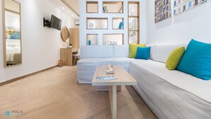 Een moderne, goed verlichte kamer met een bank, een kleine tafel en een aan de muur bevestigde televisie.