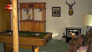 A room with a pool table, a fireplace, and a mounted deer head.